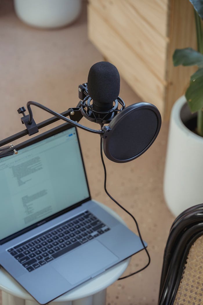 Home A modern podcast setup featuring a laptop and studio microphone on a desk, ideal for digital media production.