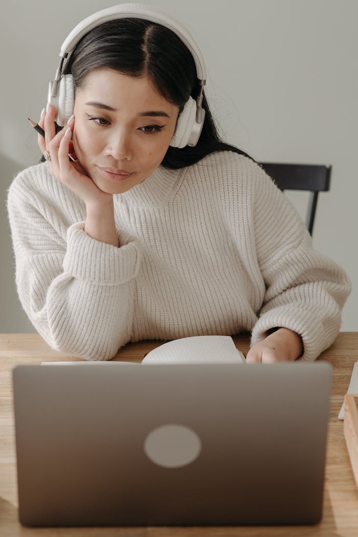 Home Woman wearing headphones working intently on a laptop indoors.